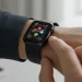 Person glancing at sleek black Apple Watch Series 9 on their wrist, with a modern blurred background.