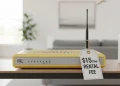 An outdated beige ISP router sits in a modern living room with a prominent '$15/mo RENTAL FEE' price tag tied to its antenna.