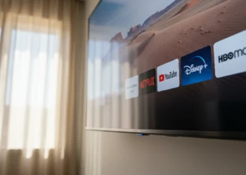 Close-up of the bright circular blue LED light on the bottom bezel of a wall-mounted Amazon Fire TV Omni indicating active microphones.