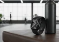 Jet Black Apple Watch Series 11 leaning against a black water bottle on a leather gym bench.