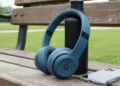 Slate Blue Beats Solo 4 bargain wireless headphones leaning on a black water bottle on a wooden park bench.