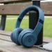Slate Blue Beats Solo 4 bargain wireless headphones leaning on a black water bottle on a wooden park bench.