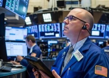 A stock trader shows concern while watching market data decline on electronic screens, illustrating the financial impact of tariffs.