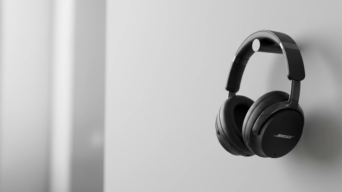 Black Bose wireless headphones hanging on a minimalist cylindrical wall mount.